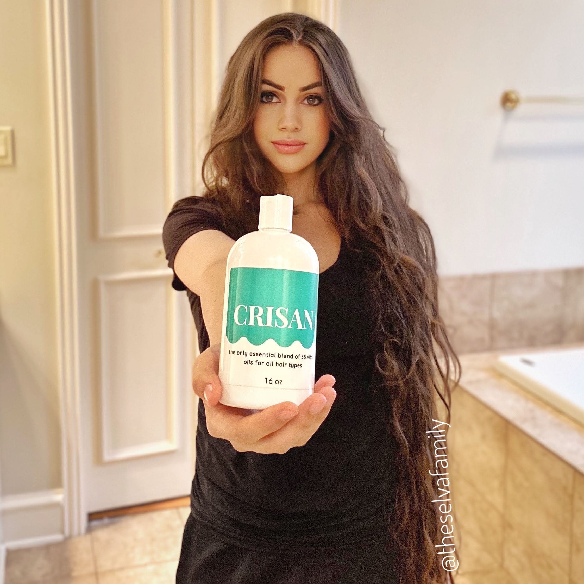 Woman holding a bottle of CRISAN product in a bathroom setting