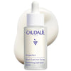 Caudalée Vinoperfect brightening dark spot serum in a frosted glass dropper bottle with a white cap, set against a white background with a soft cream-colored droplet shape behind it.