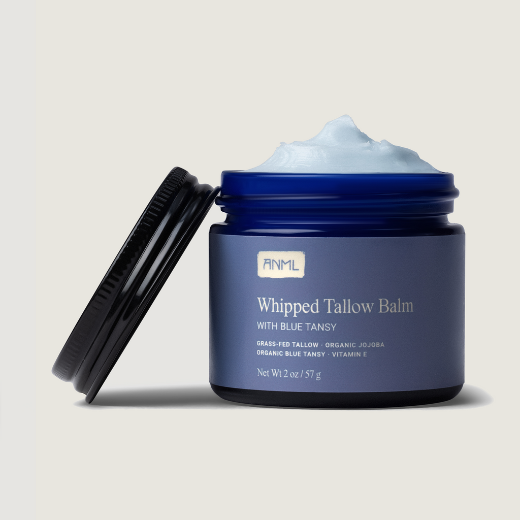 Blue jar of whipped tallow balm with visible brand name on a beige background