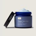 Blue jar of whipped tallow balm with visible brand name on a beige background