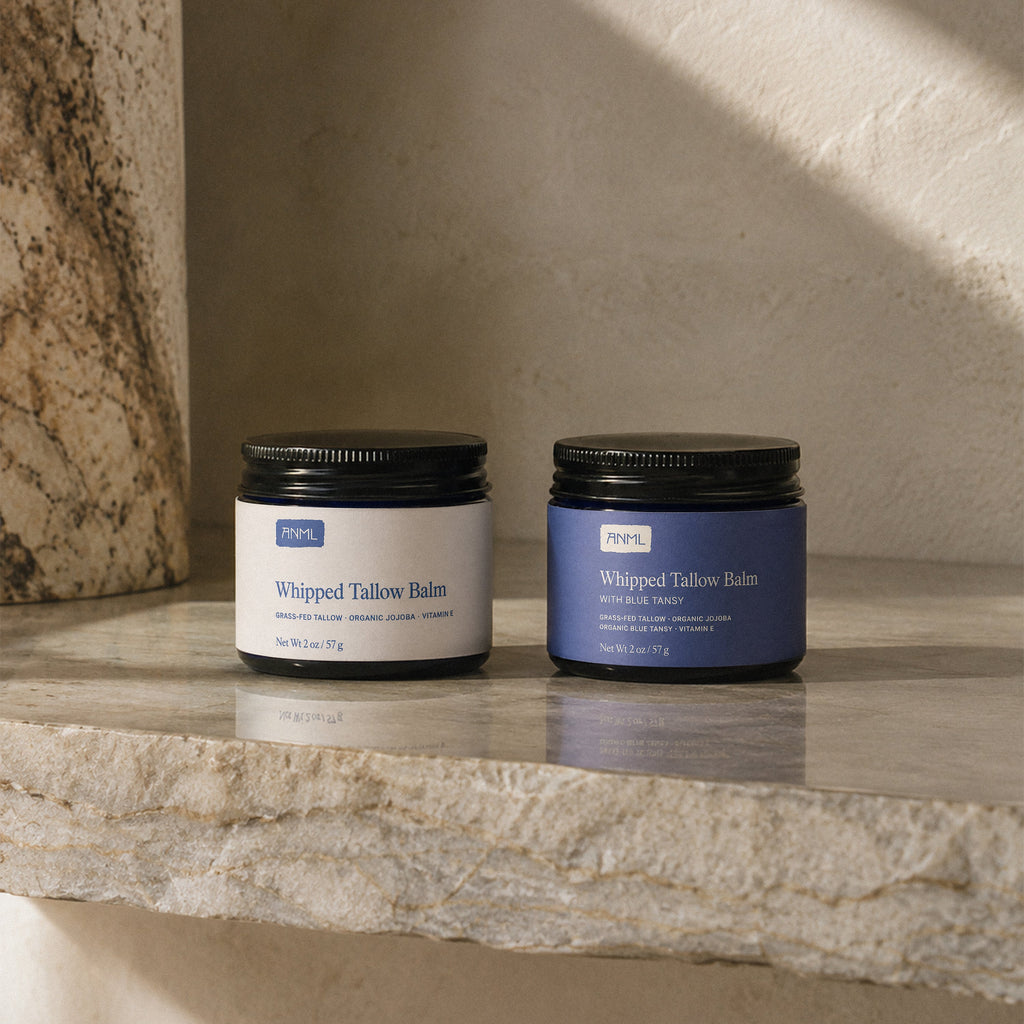 Two jars of 'Whipped Tallow Balm' on a stone surface