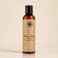A 120mL amber bottle of Timeless Organics Skin Care Anti-Aging Cleanser with a black cap and a textured beige label featuring a black dandelion illustration, set against a solid cream background.