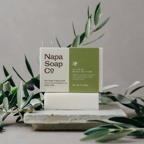 Napa Soap Co. bar soap on a stone surface with greenery in the background