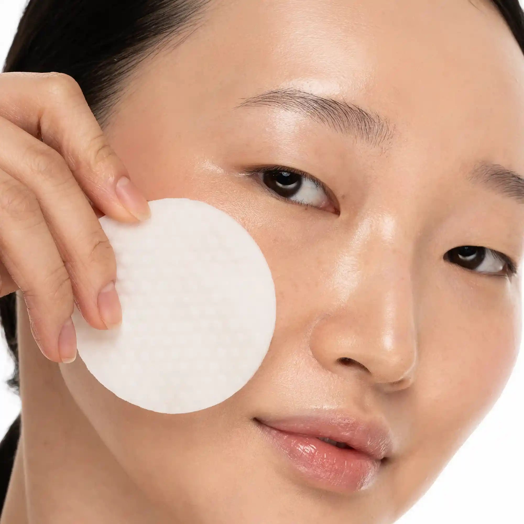 Person applying a white patch to their face with a neutral background