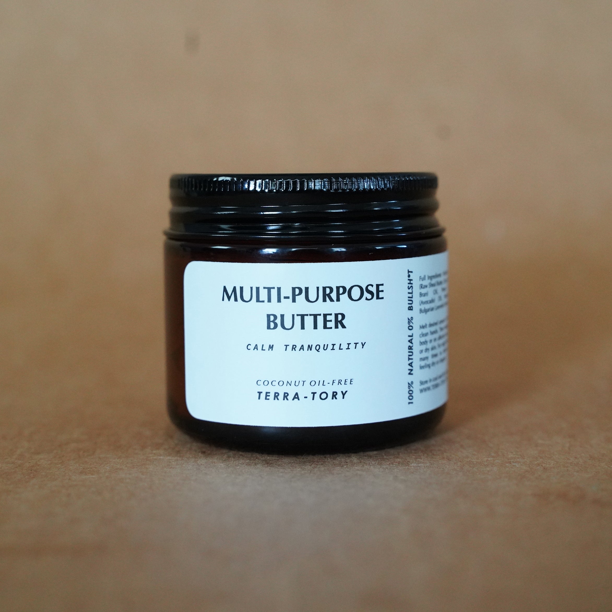 Black jar of multi-purpose butter with a white label on a brown background