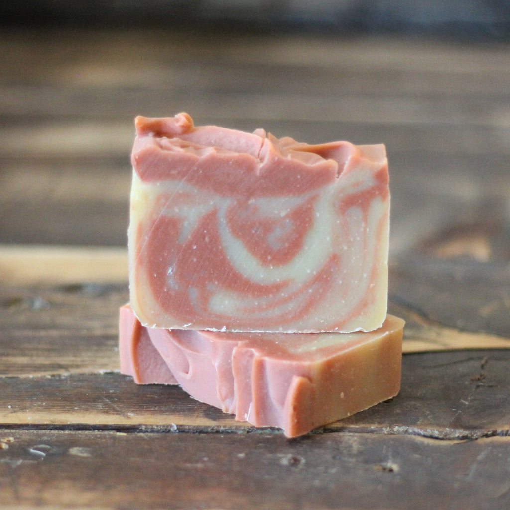 Pink and white swirled soap bar on a wooden surface