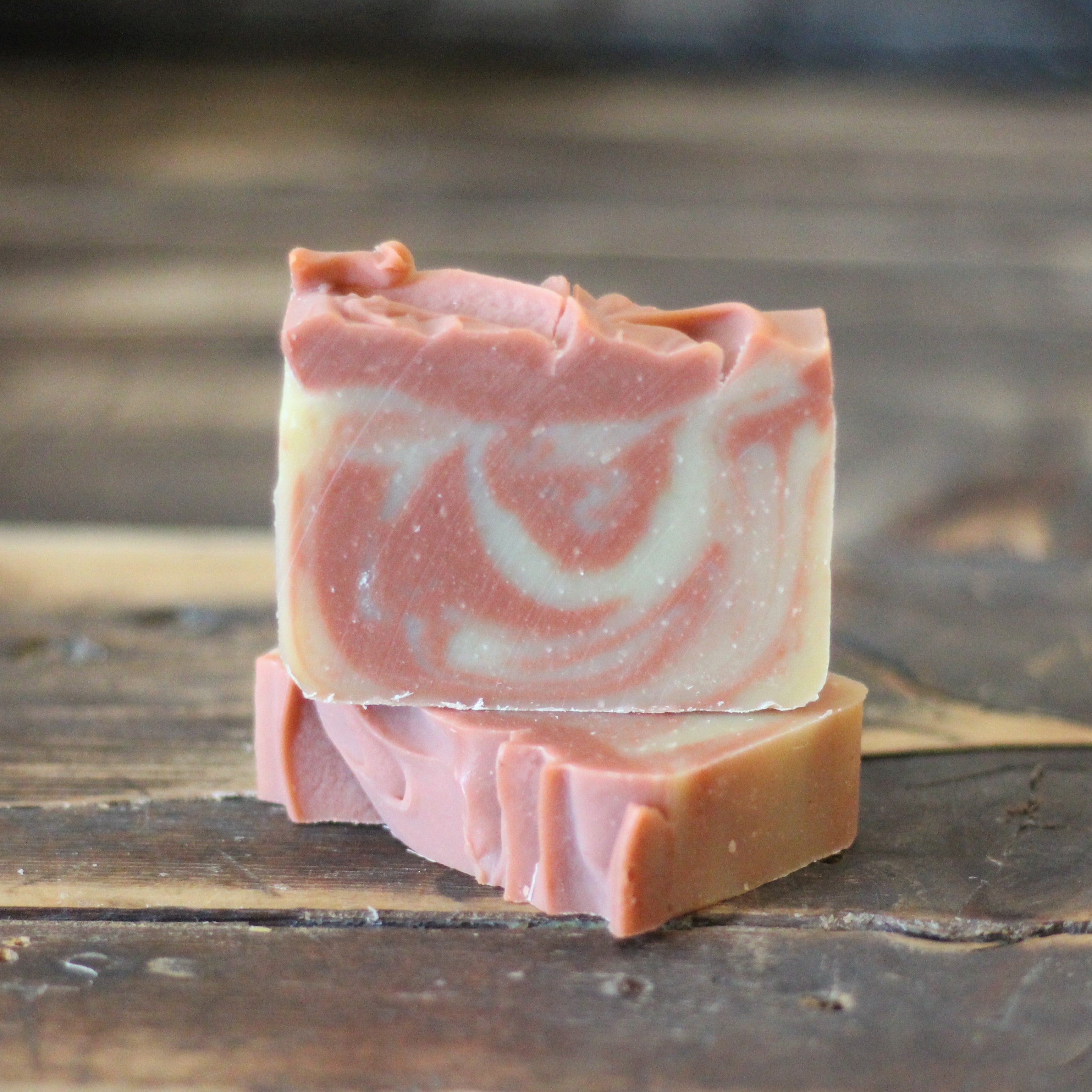 Pink and white swirled soap bar on a wooden surface
