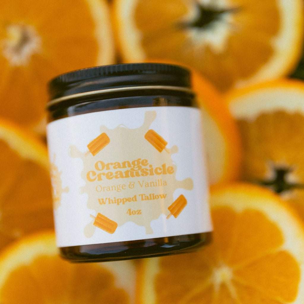 Jar of Orange Creamsicle whipped tallow with orange slices in the background