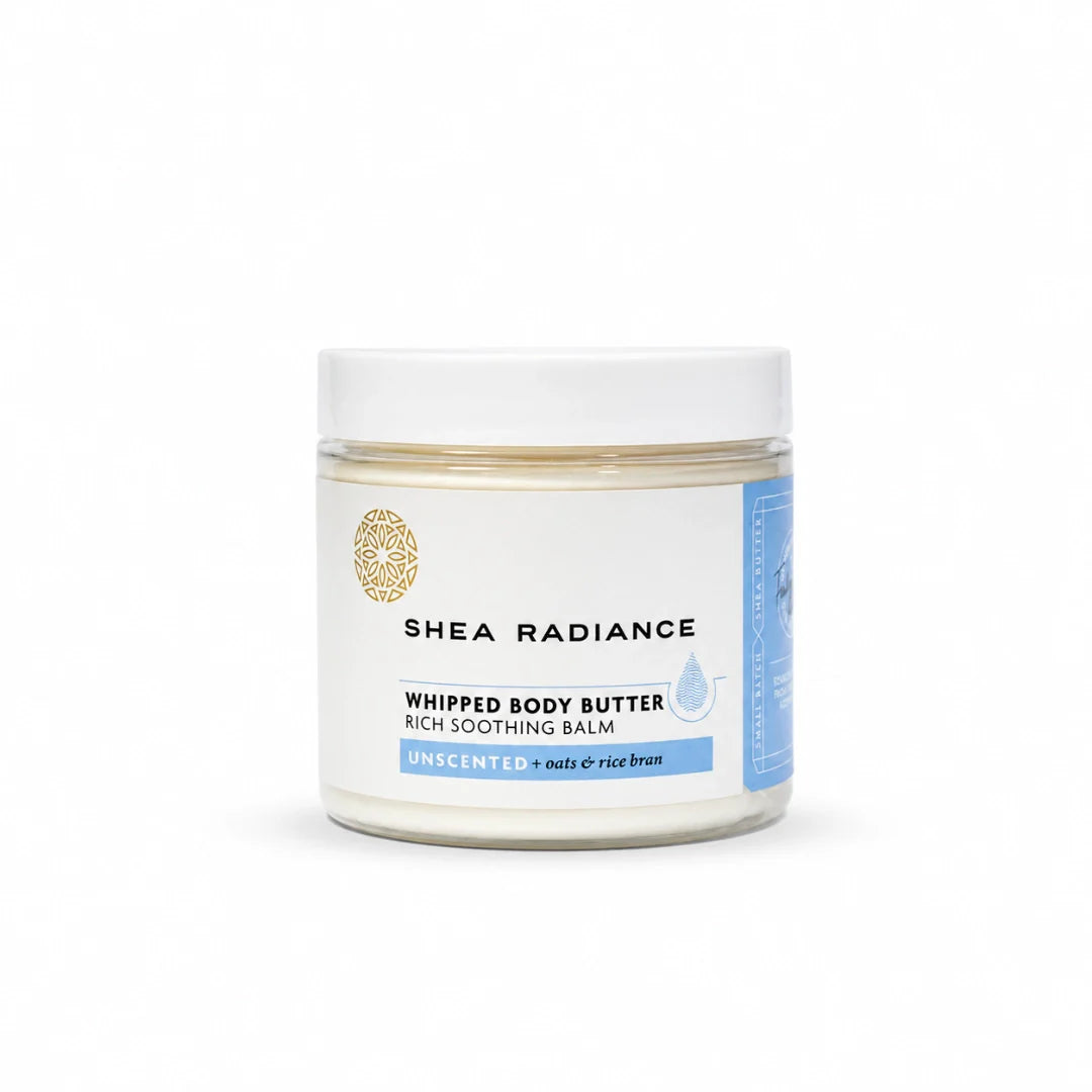 A jar of Shea Radiance Whipped Body Butter rich soothing balm, unscented, with a white lid and white label featuring light blue and gold accents, on a white background.