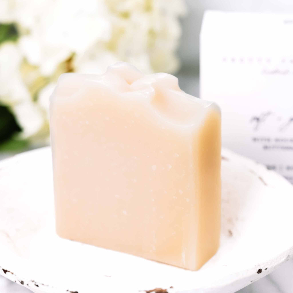 Bar of soap on a white plate with a blurred floral background