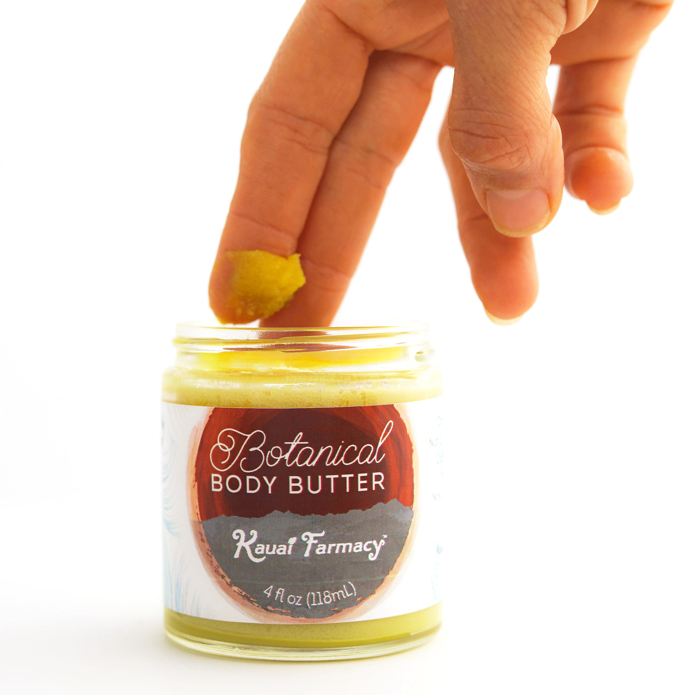 Hand applying Botanical Body Butter from Kauai Farmacy jar on a white background
