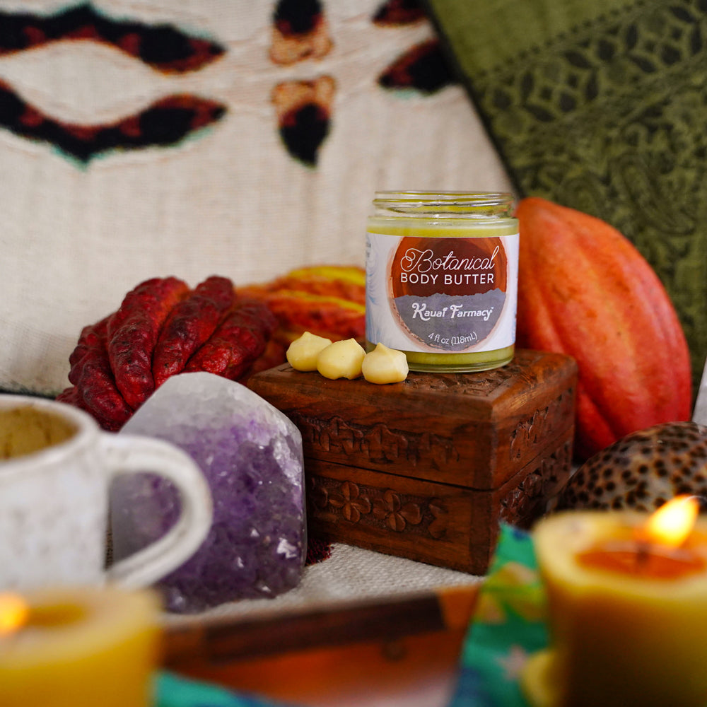 Jar of Botanical Body Butter on a wooden block with decorative items and candles in the background.