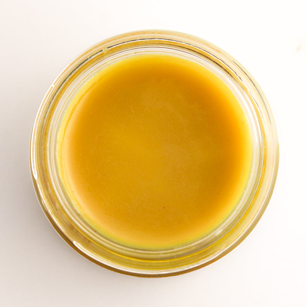 Glass jar filled with a yellowish liquid on a white background