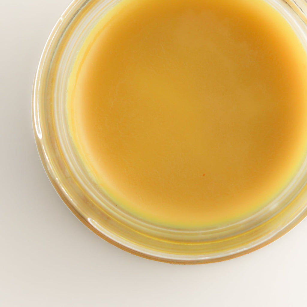 Yellow substance in a glass jar on a light gray background