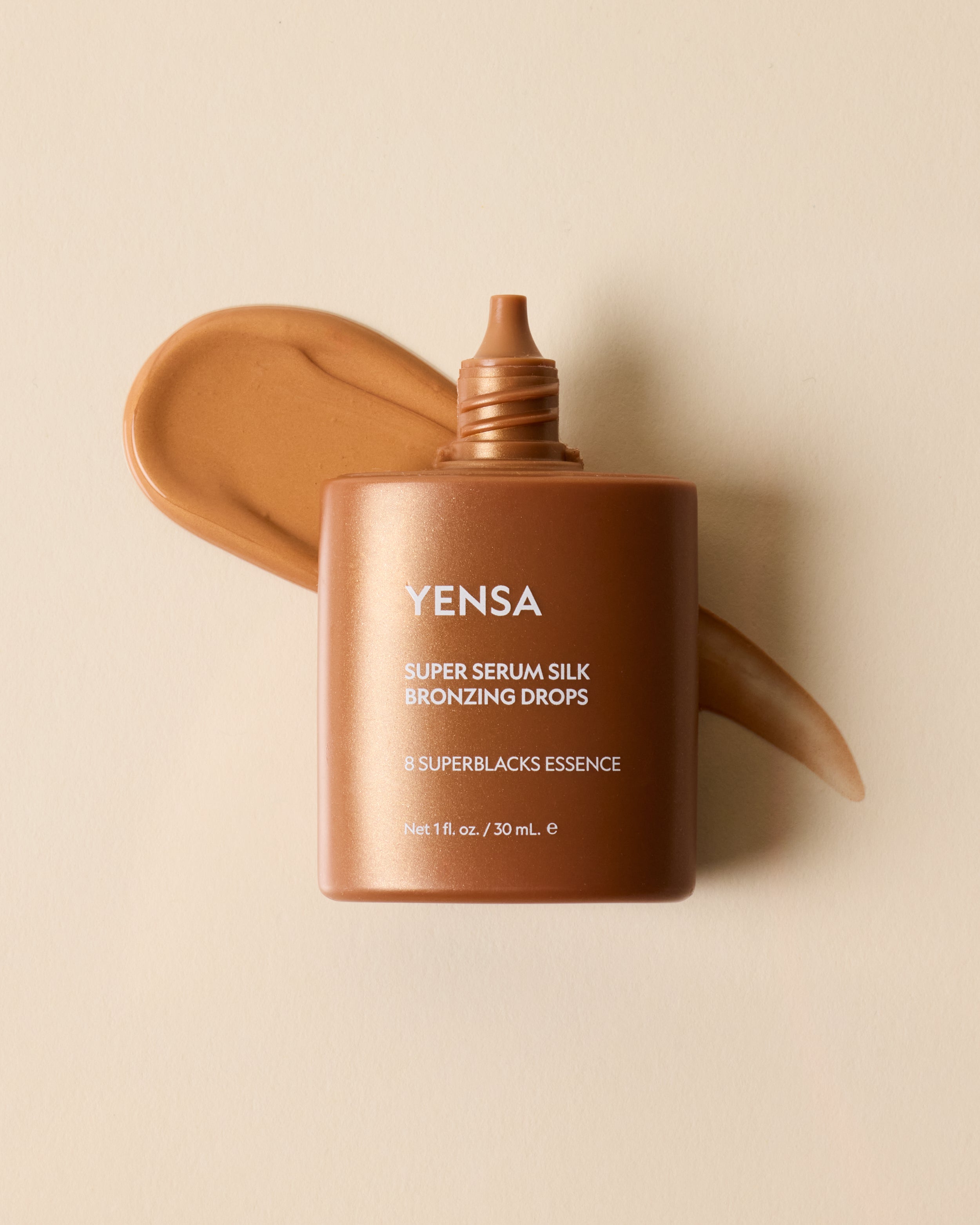 Yensa Super Serum Silk Bronzing Drops bottle with a swatch on a beige background