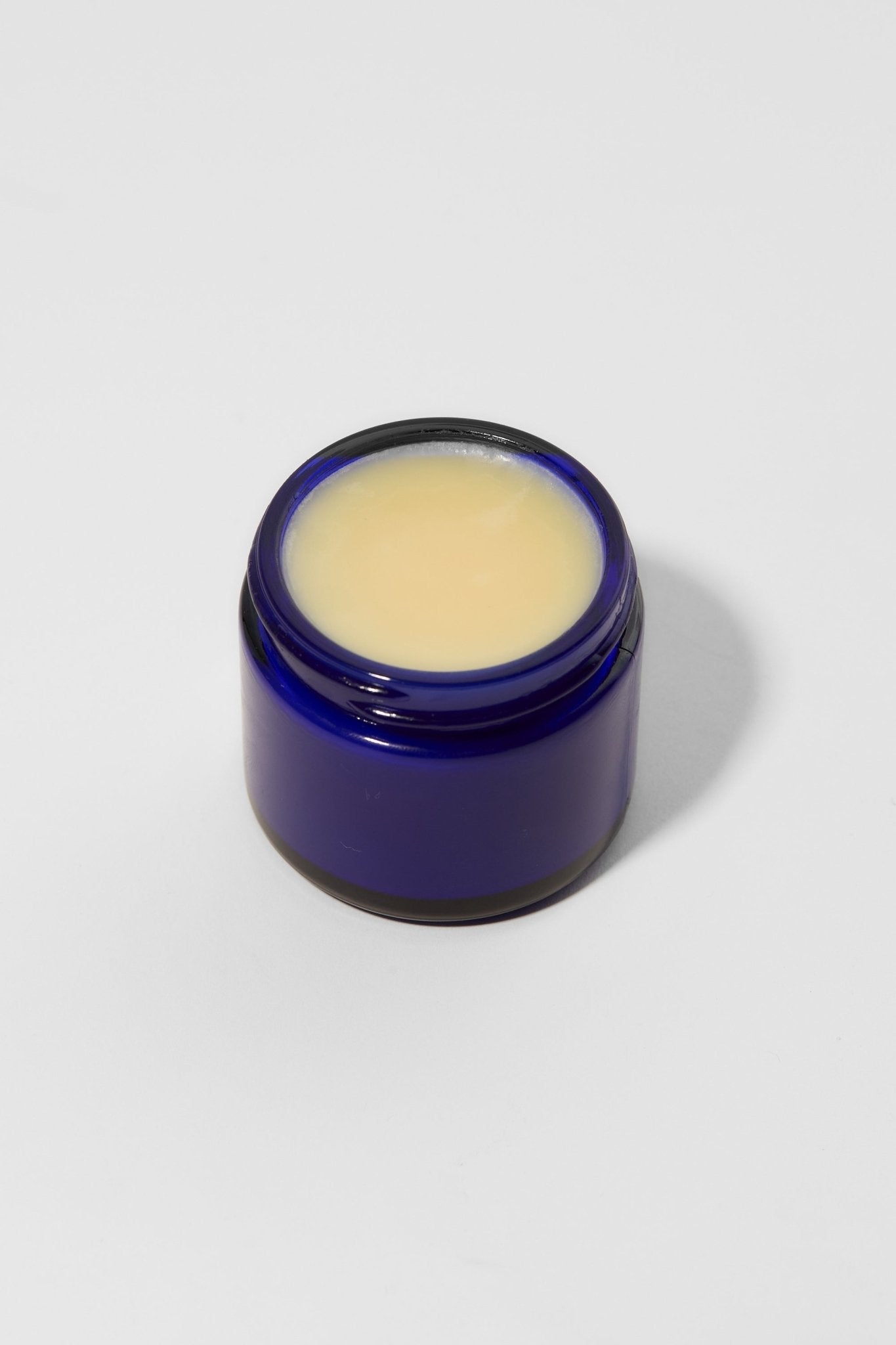 Blue jar with a white cream inside on a light gray background