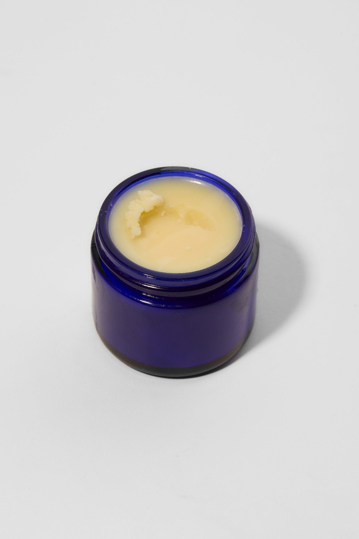 Blue jar with a white cream inside on a light gray background